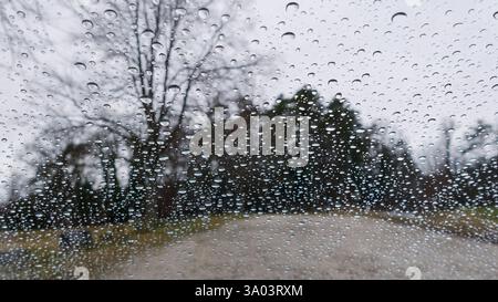 Raindrops on Glass with Blurred Outdoor Scenery in Background Stock Photo