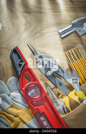 Assortment of construction tooling in leather tool belt on wooden board Stock Photo