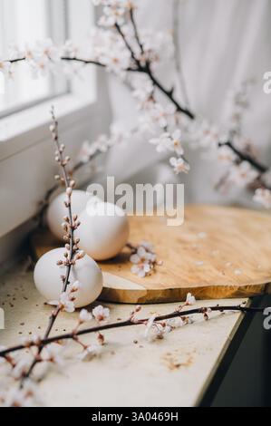 Beautiful branches lie on a wooden board on the windowsill. Composition with Easter eggs and bunny. Spring greeting background with place for text. Stock Photo