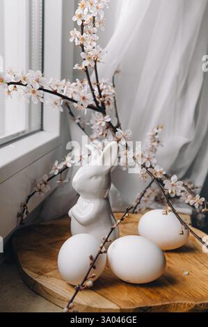 Beautiful branches lie on a wooden board on the windowsill. Composition with Easter eggs and bunny. Spring greeting background with place for text. Stock Photo