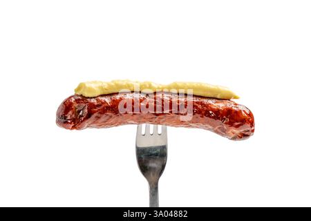 Sausage with mustard on a fork. Fork with sausage isolated on white background. Stock Photo
