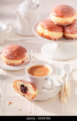 Traditionally doughnuts served with coffee in kitchen. Donuts with jam and sweet topping. Stock Photo