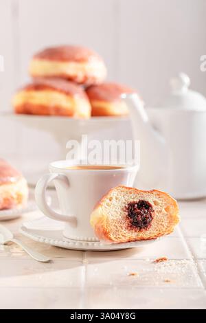 Hot doughnuts served with coffee in kitchen. Donuts with jam and sweet topping. Stock Photo