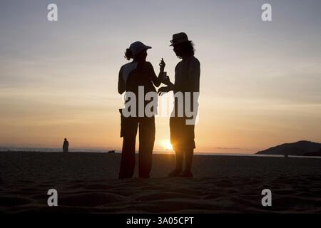 Two silhouette human figure talking near sunset, Palolem beach, Goa, India, Asia Stock Photo
