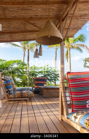 Lounge chairs with pillows and wooden table on the terrace. Cozy patio in hotel resort. Empty tourist villa. Outdoor design of luxury hotel. Stock Photo
