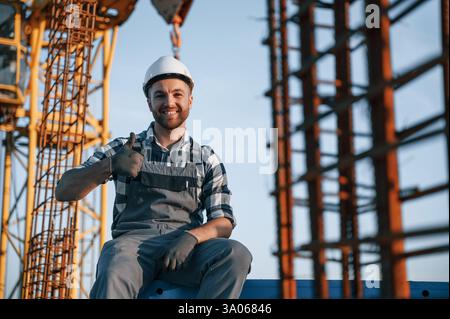 Sitting and smiling. Man is working on the construction site at daytime. Stock Photo