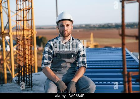Sitting and taking a break. Man is working on the construction site at daytime. Stock Photo