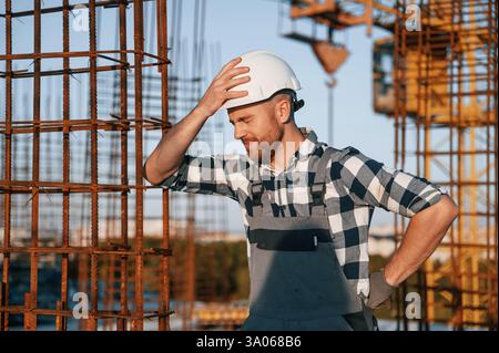 Feeling bad. Having headache. Man is working on the construction site at daytime. Stock Photo