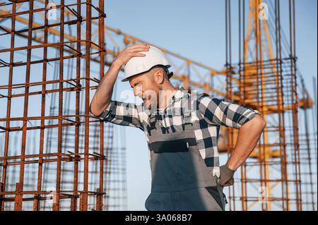 Feeling bad. Having headache. Man is working on the construction site at daytime. Stock Photo