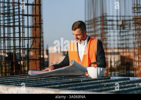 Man is working on the construction site at daytime. Reading the plan. Stock Photo