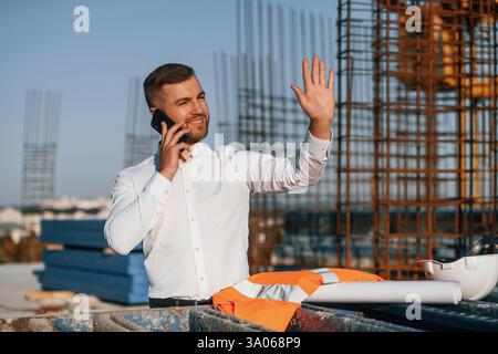 Businessman in formal clothes is on the construction site at daytime. Stock Photo