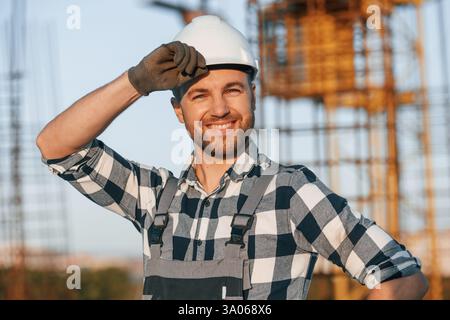 Happy worker is standing on the construction site at daytime. Stock Photo