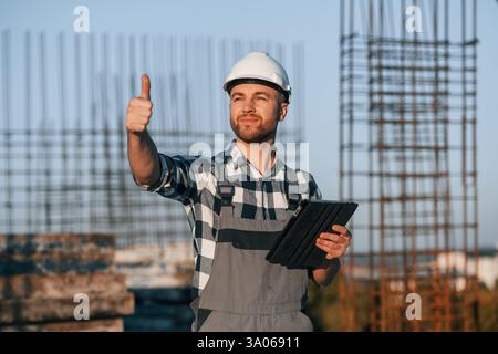 Showing thumb up. Man is working on the construction site at daytime. Stock Photo