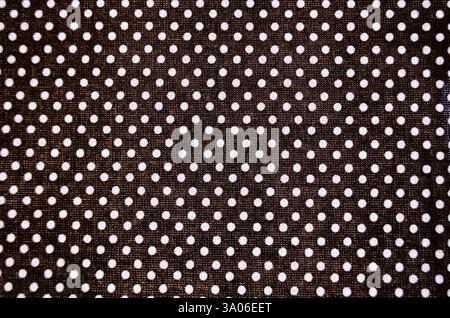 Full frame close-up of black and small white polka dots on woven fabric overhead view Stock Photo