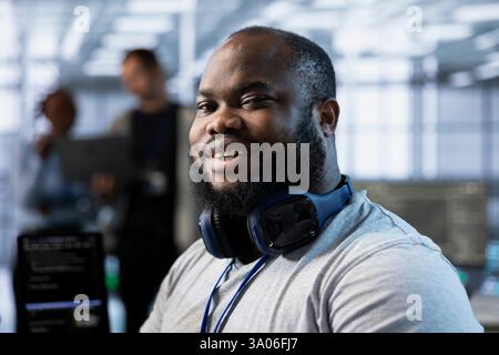 Portrait of smiling engineer in server room implementing power management solutions to reduce energy consumption. Happy IT specialist integrating new technologies in data center, close up Stock Photo