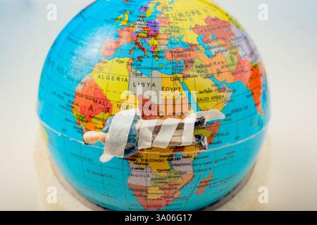 Tiny figurine of man  model wrapped in bandages  on earth Stock Photo