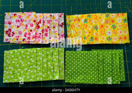 Above view of layered fabric squares for a quilt layering on cutting mat. Stock Photo