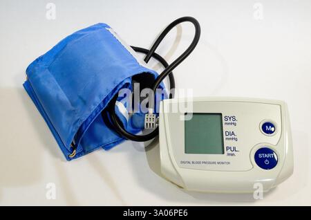 Close-up view from above of a blood pressure monitor with a blue arm cuff against a white background Stock Photo