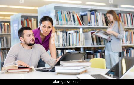 Two male and female students studying together in library Stock Photo
