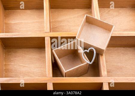 Open cardboard box inside a wooden box with compartments and a heart Stock Photo
