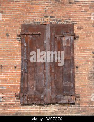 Old, metal shutters with worn hinges in a brick wall. Stock Photo