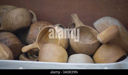 A collection of hand-carved wooden cups and bowls are arranged on a shelf, showcasing the natural wood grain. Stock Photo