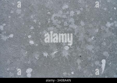 Close-up of concrete wall with white paint splashes and rough texture. Background for construction and renovation concept Stock Photo