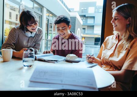 Young students participate in group work in the school cafeteria, fostering collaboration and creativity in a modern collaborative setting. Stock Photo