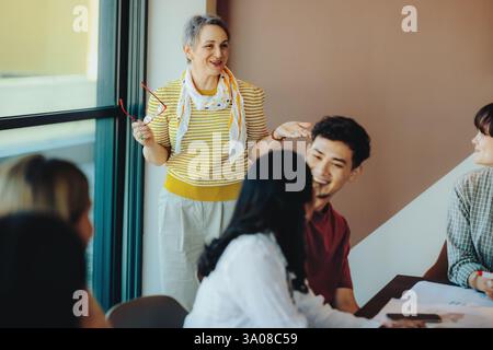 A joyful high school teacher interacts with students during an engaging classroom session, fostering a positive learning environment. Stock Photo