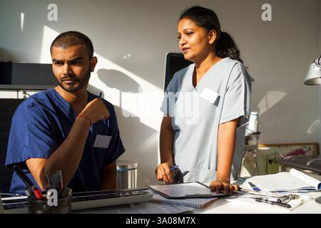 Female physician standing near male doctor while discussing in medical clinic at hospital Stock Photo