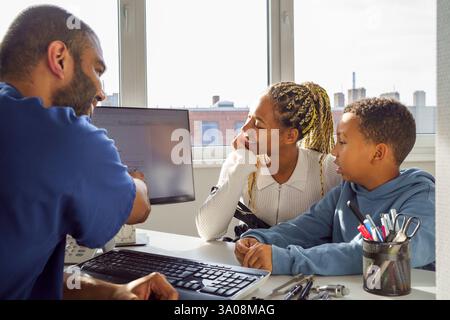 Male pediatrician discussing medical test results with mother and son in clinic Stock Photo