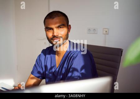 Portrait of serious male medical professional sitting on chair in clinic Stock Photo