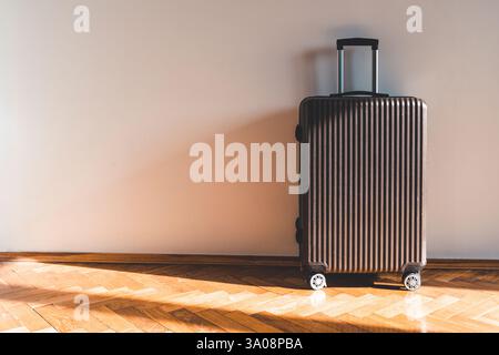 Suitcase for travel and vacation against light wall in room on sunny day. High quality photo Stock Photo
