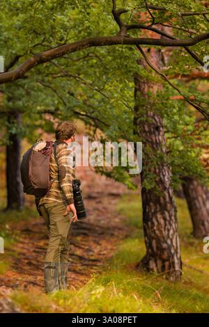 Nature photographer. Young male photographer autumn season outdoors portrait. Back view. Landscape photographer taking photos. Stock Photo