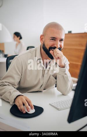 Portrait of happy male entrepreneur sitting at desk in office Stock Photo