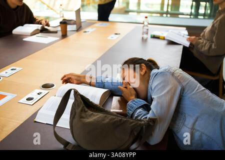 High angle view of tired female student sleeping on desk in library Stock Photo