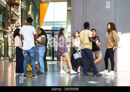 Full length of multiracial students discussing while standing in college campus Stock Photo