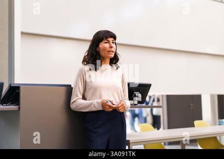 Confident female teacher explaining while standing in lecture hall at university Stock Photo