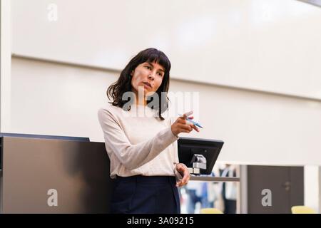 Confident female teacher explaining while pointing in lecture hall at university Stock Photo