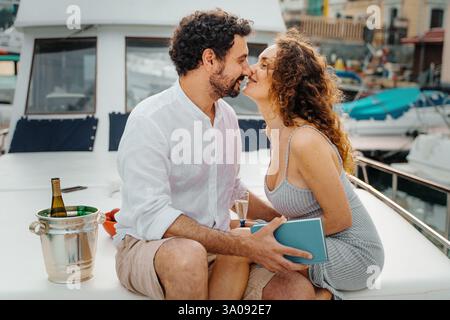 A romantic couple enjoying a luxury yacht experience at the marina, sharing an intimate and joyful moment on vacation. Stock Photo