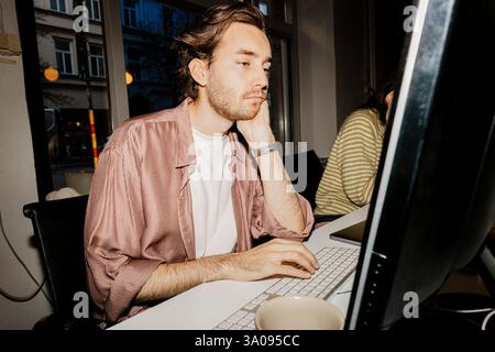 Tired male entrepreneur using computer at desk in office Stock Photo