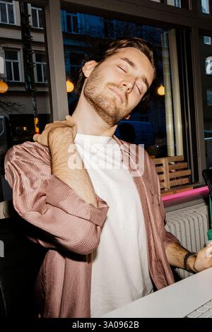 Tired businessman stretching neck while at desk in office Stock Photo