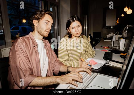 Male and female entrepreneurs working together on computer at office Stock Photo