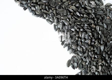 Black Unpeeled Sunflower Seeds on White Background, Place for Text, Top View. Stock Photo