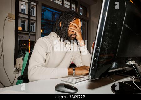 Sad male entrepreneur with head in hand while sitting at desk in office Stock Photo