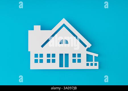 House shaped paper cutout on light blue background. Minimal concept. Flat lay style. Top view banner. Stock Photo