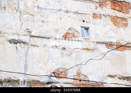 Weathered Building Facade with Exposed Bricks and Window Stock Photo