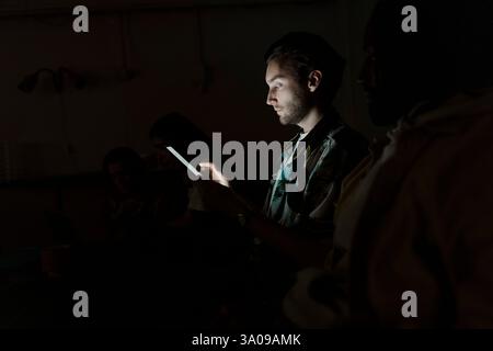 Young male entrepreneur using smart phone in dark room Stock Photo