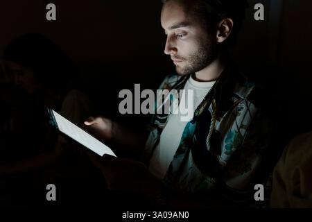 Male entrepreneur using tablet PC in darkroom Stock Photo