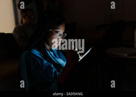 Female business professional using tablet PC in darkroom Stock Photo